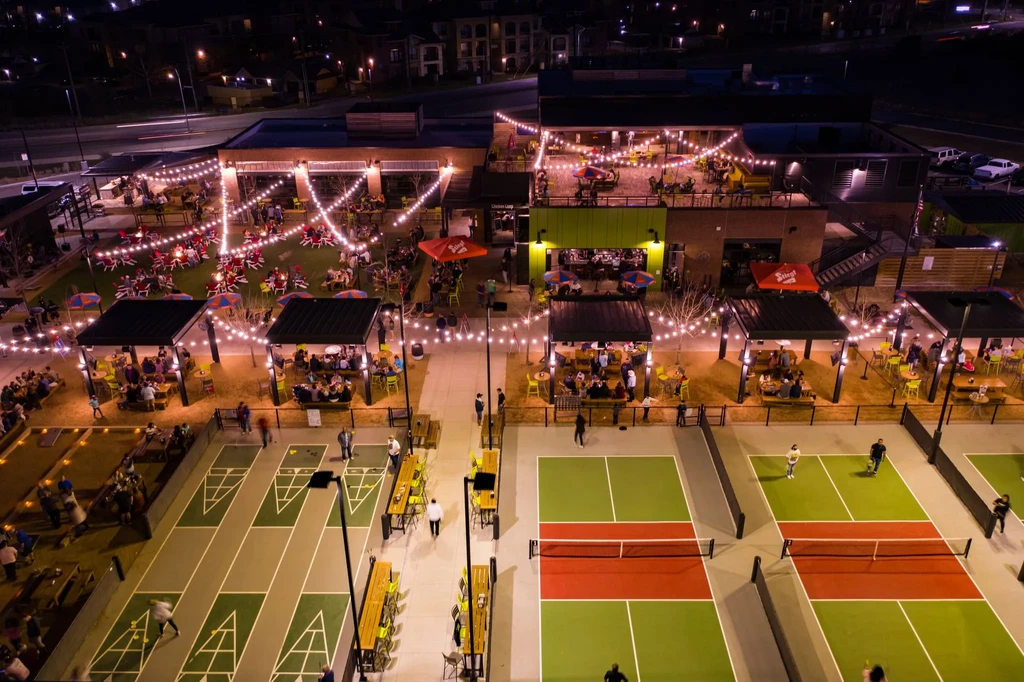 Aerial night view of a lively outdoor dining and recreation complex.