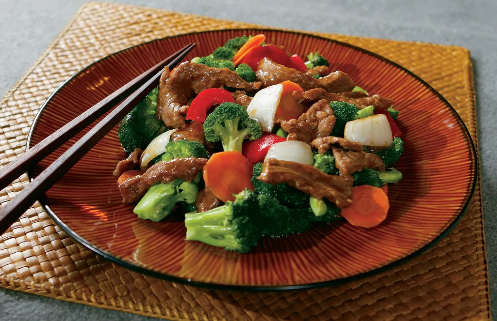 Colorful beef and broccoli stir-fry with chopsticks on a plate.