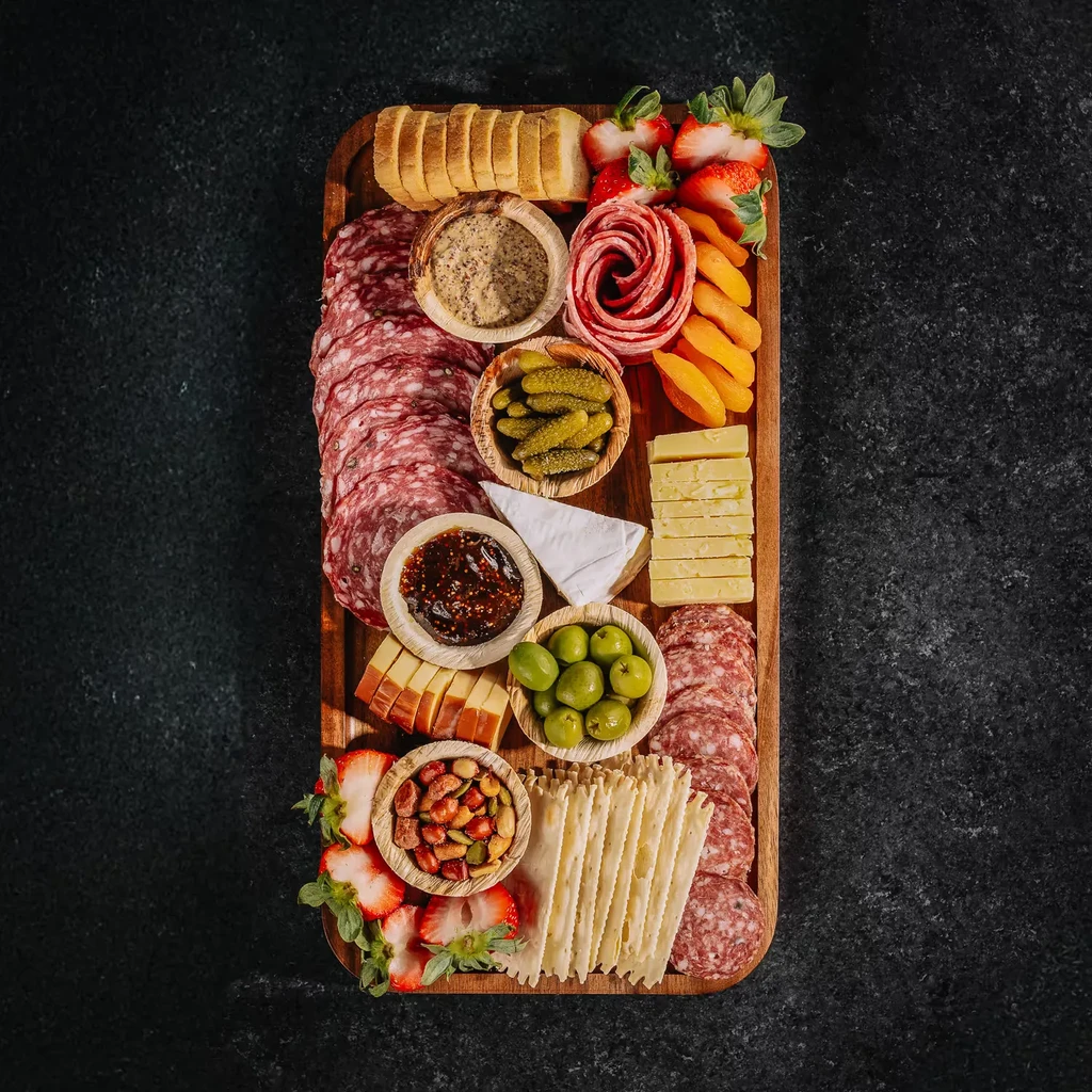 Beautifully arranged charcuterie board with meats, cheeses, fruits, and crackers.