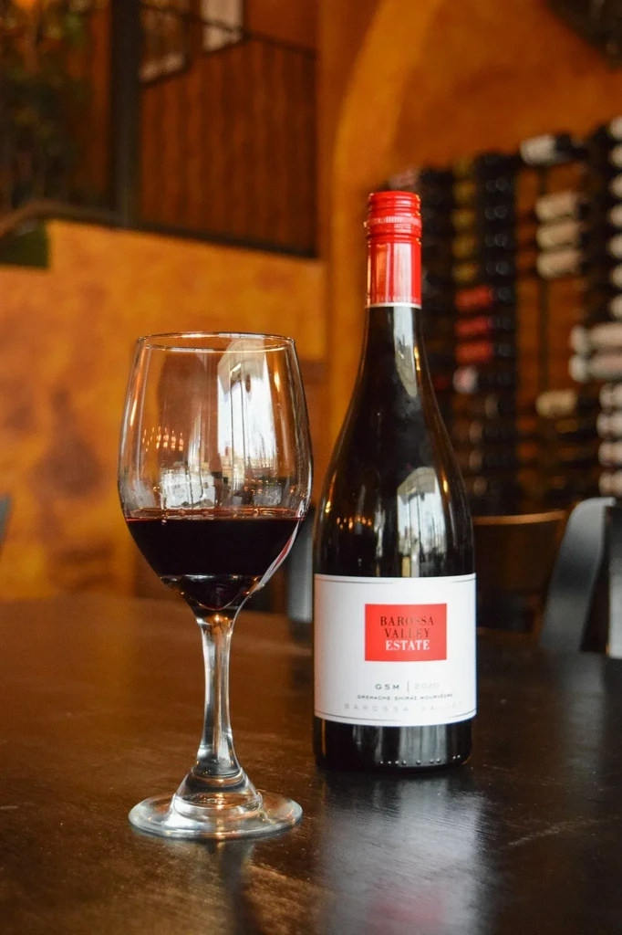 Barossa Valley Estate GSM wine bottle and glass in a restaurant.