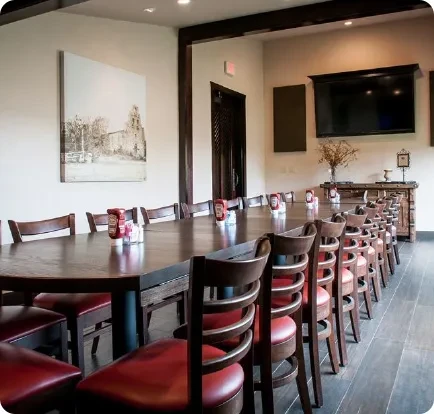 Long dark wooden communal dining table in a well-lit private room.