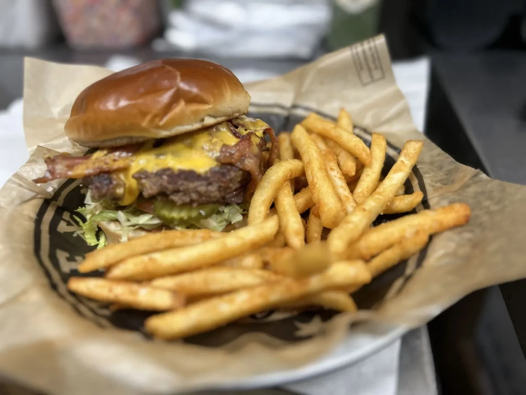 Close-up bacon cheeseburger, melted cheese, crispy bacon, and golden fries.