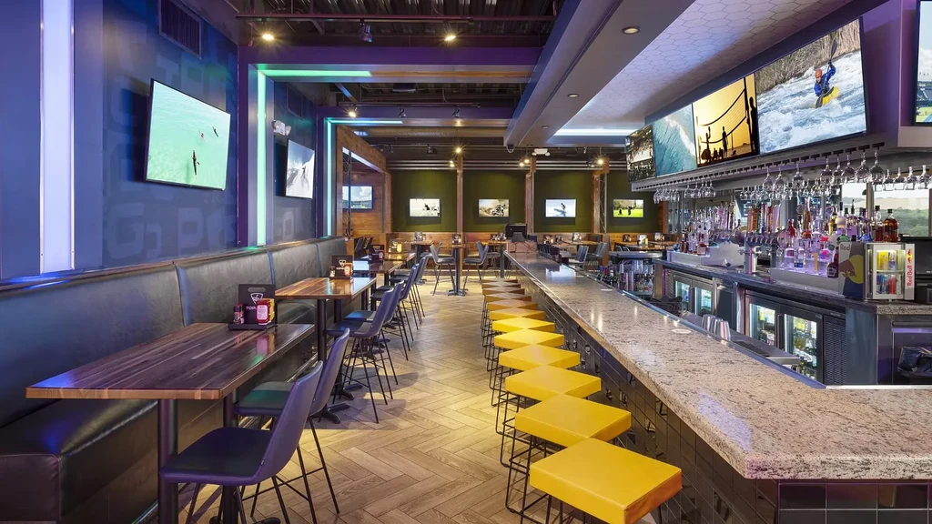 Empty modern sports bar with booths, long bar, and sports TVs.