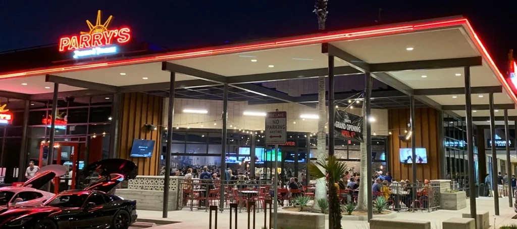 Parry's restaurant exterior at night with red neon, patio, and sports cars.