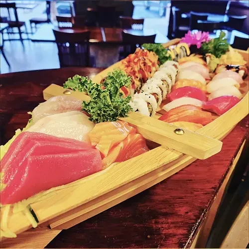 Assorted sushi and sashimi platter on a wooden boat at a restaurant.