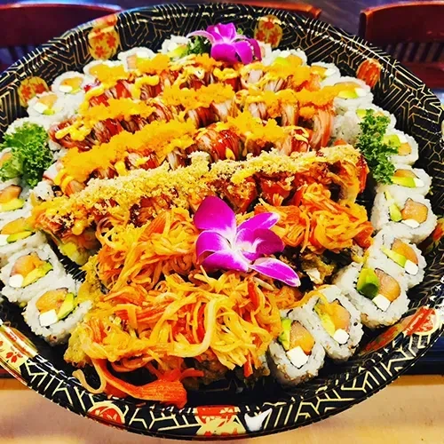 Assorted sushi rolls, crab salad, and orchids on an ornate black platter.