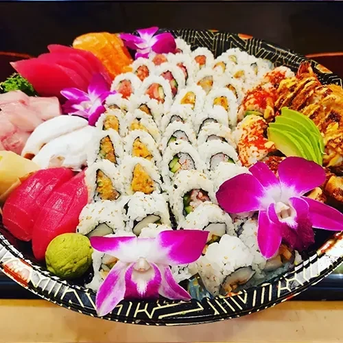 Large platter of sushi, sashimi, grilled items, and orchid garnish.