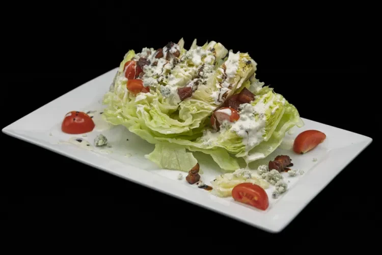 Wedge salad with blue cheese, bacon, tomatoes, and balsamic glaze.