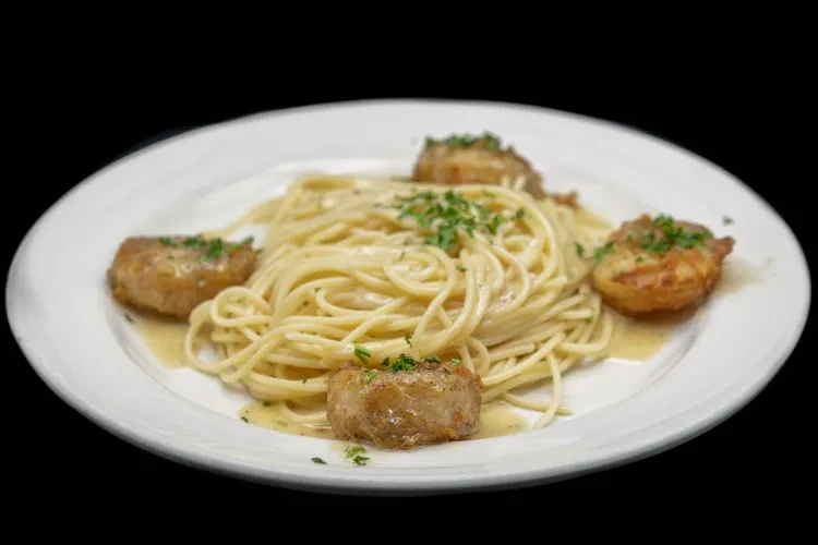 Spaghetti with creamy sauce and pan-seared scallops garnished with parsley.
