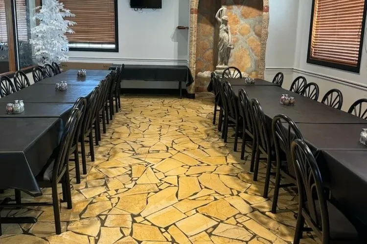Prepared banquet room with two tables, classical statue, and bare tree.