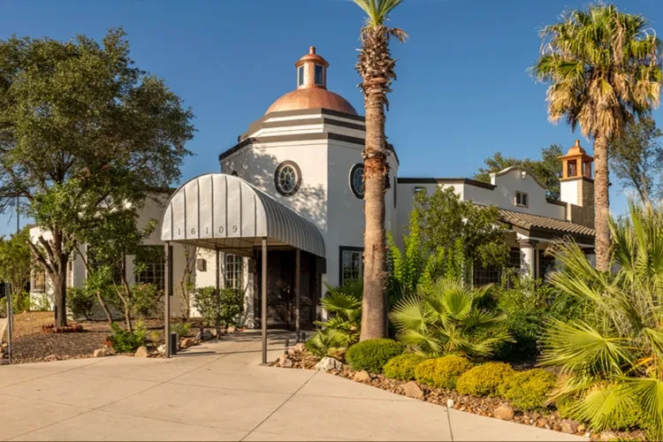 White octagonal building with copper domes, 16109, and tall palm trees.