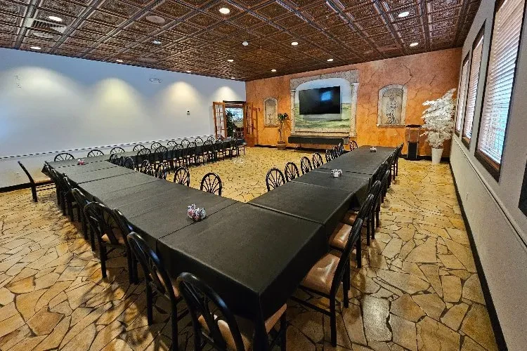 Empty event room with U-shaped table, flagstone floor, and decorative ceiling.