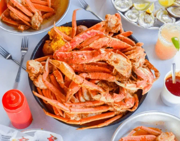 Overhead view of snow crab legs, corn, potatoes, and fresh oysters.