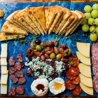 Vibrant charcuterie board with cheeses, meats, fruits, olives, and bread.