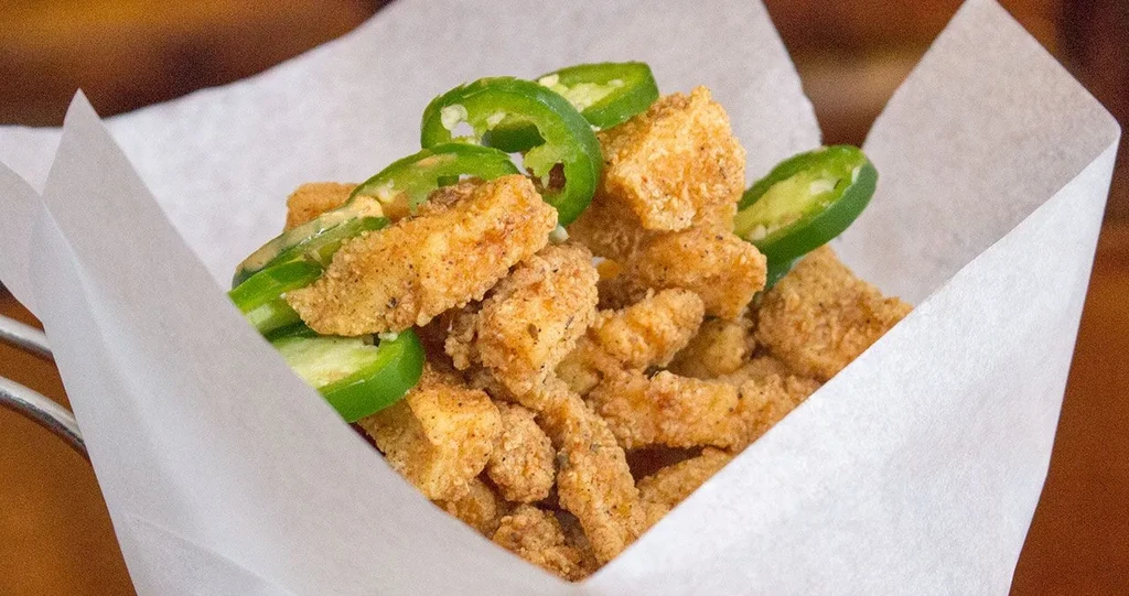 Crispy, breaded fried food with fresh jalapeño in a basket.