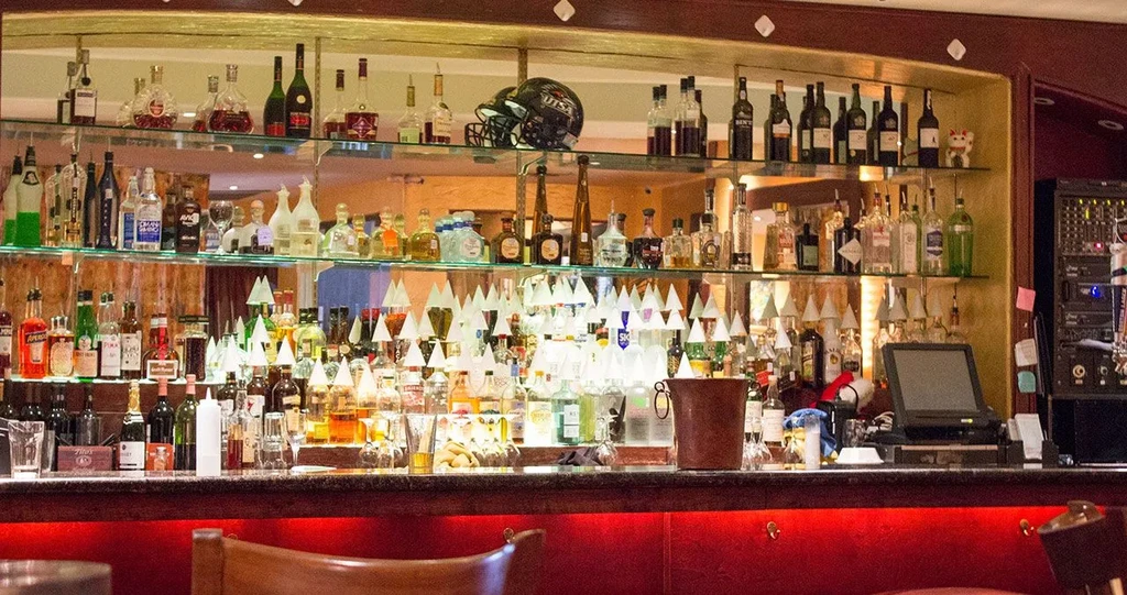 Well-stocked bar with spirits, football helmets, and a Maneki-neko.