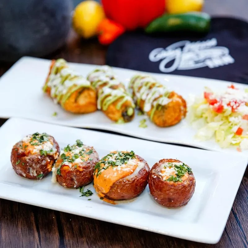 Two plates of fried food with sauces, cheese, and fresh herbs.