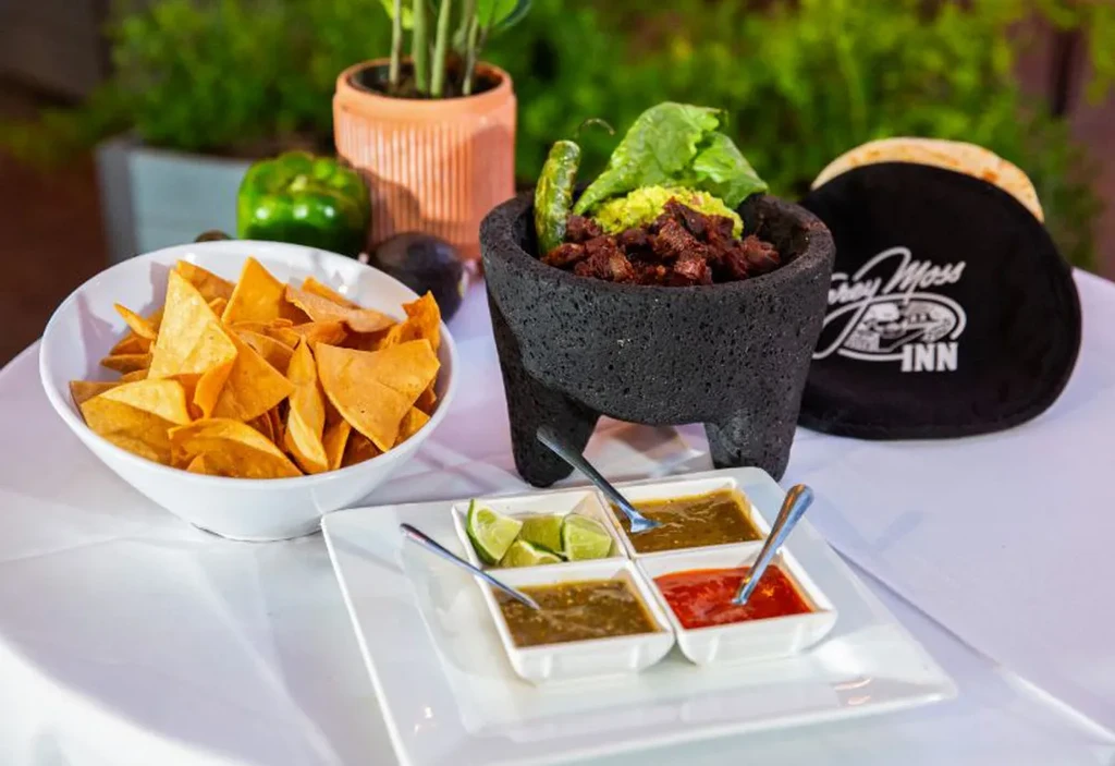 Outdoor Mexican food spread with chips, molcajete, salsas, and warmer.