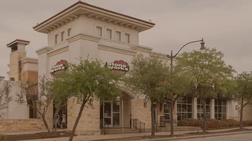 Stone Werks building exterior, light walls, red-tiled tower, overcast day.