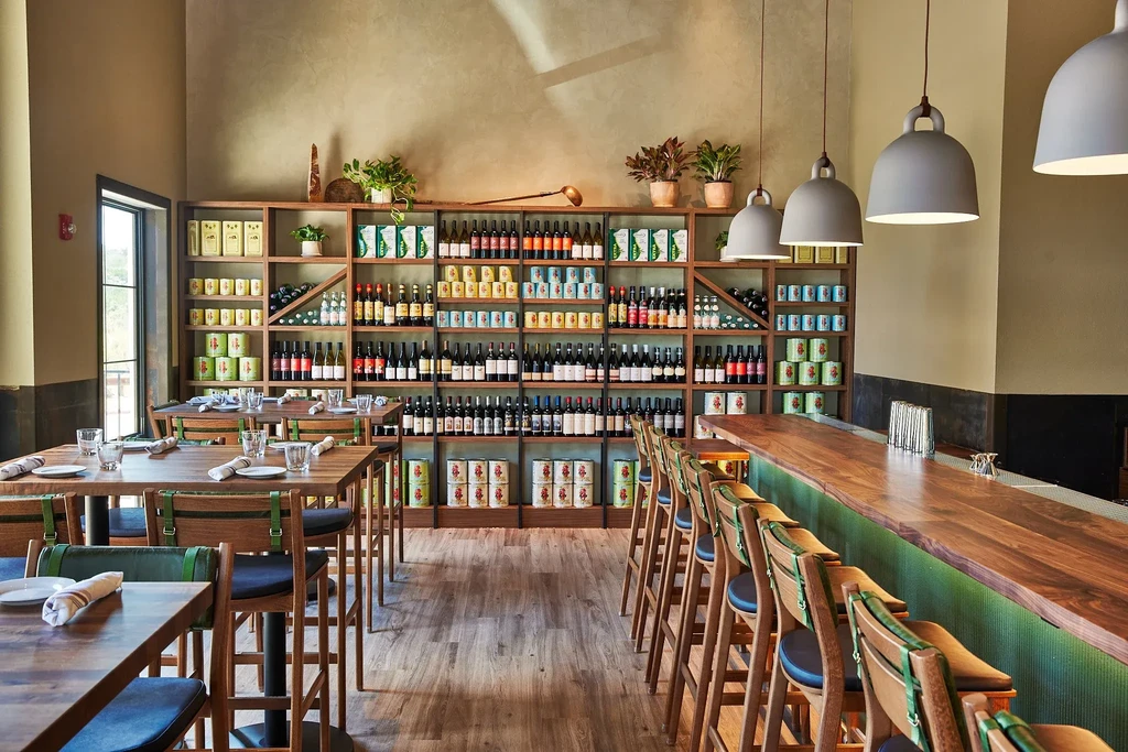 Clean, modern restaurant interior with dining area, bar, and stocked shelves.