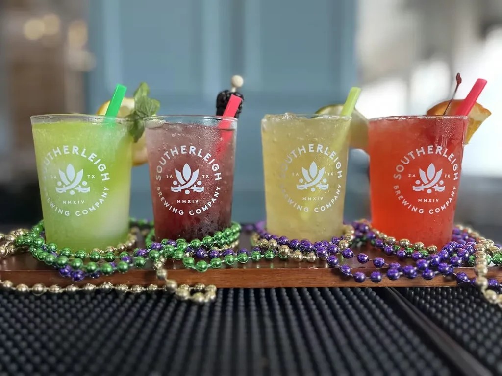 Four colorful Southerleigh Brewing Co. drinks, Mardi Gras beads, on wood.