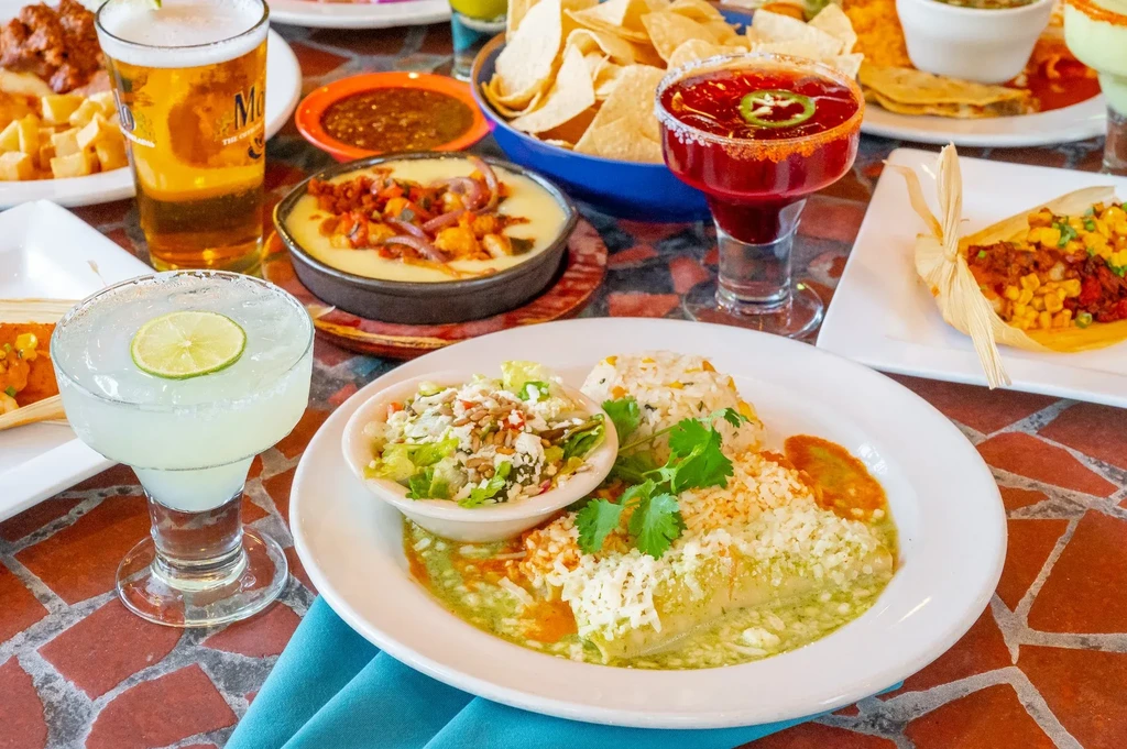 Assortment of vibrant Mexican dishes and drinks on a restaurant table.