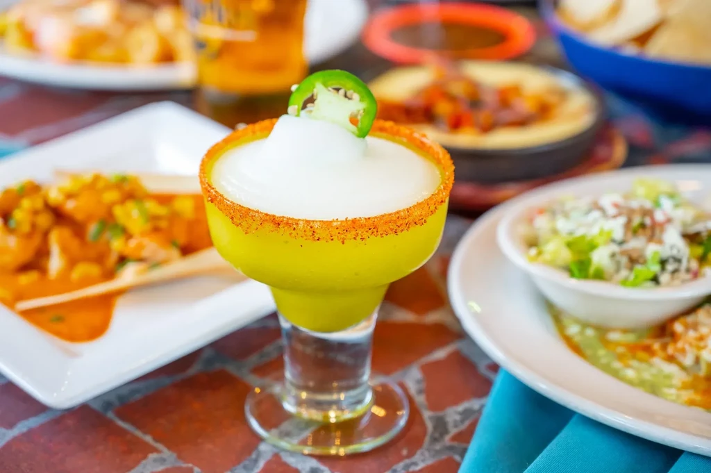 Frozen lime margarita with a spiced rim and jalapeño garnish.
