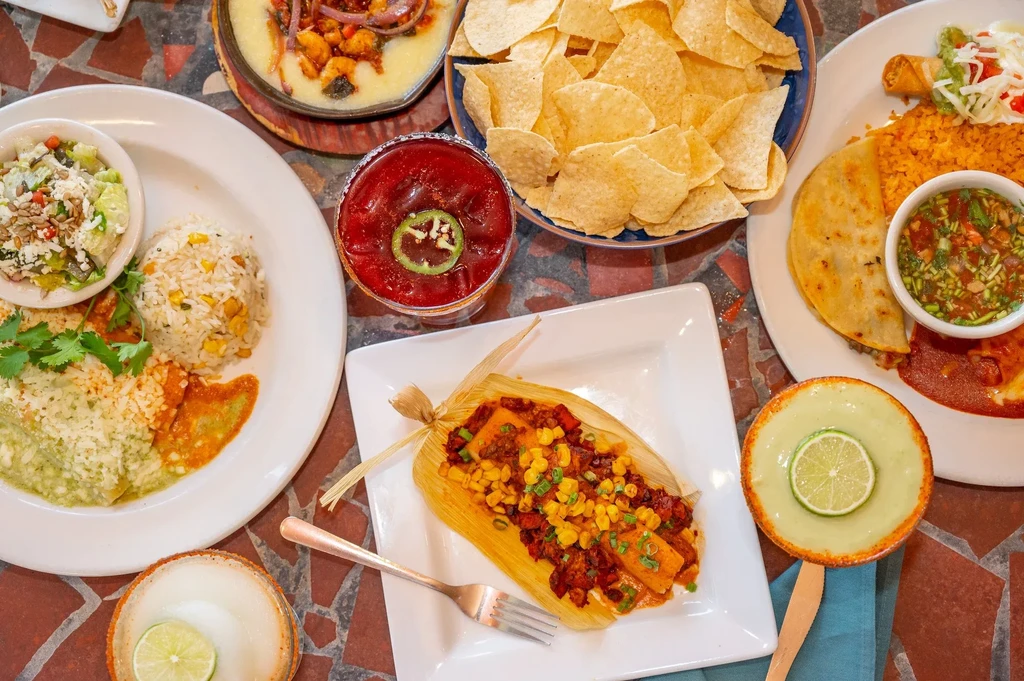 Vibrant Mexican food and drinks on a mosaic-tiled table.