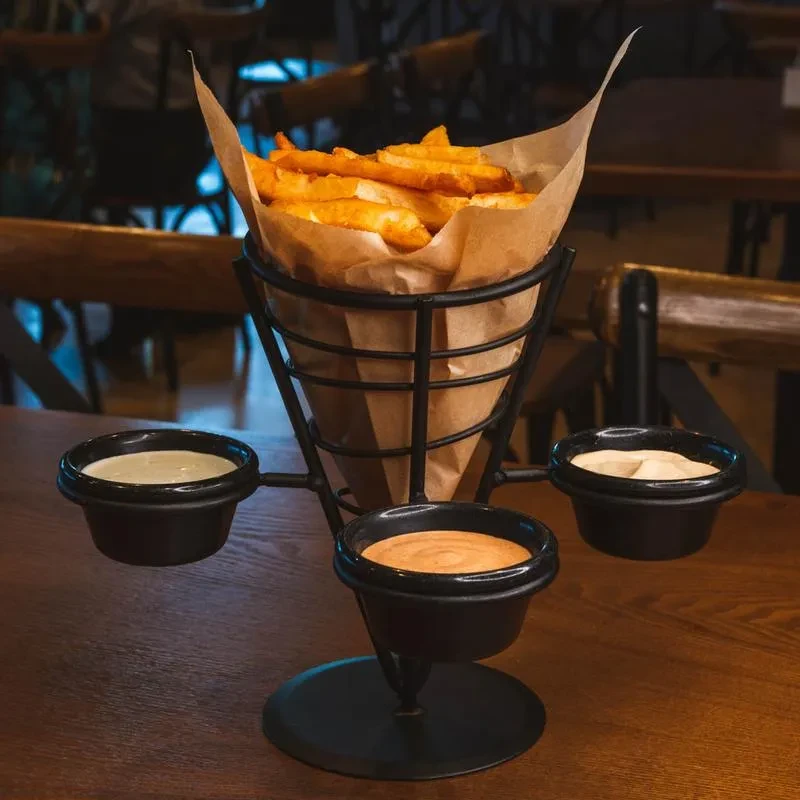 Golden-brown french fries in a paper cone with three dips.