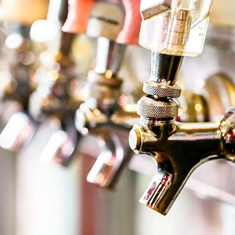Multiple reflective beer taps lined up in a clean bar.