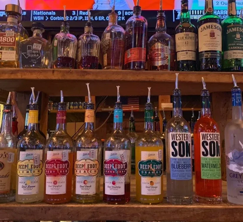 Well-stocked bar counter with shelves of liquor bottles and pour spouts.