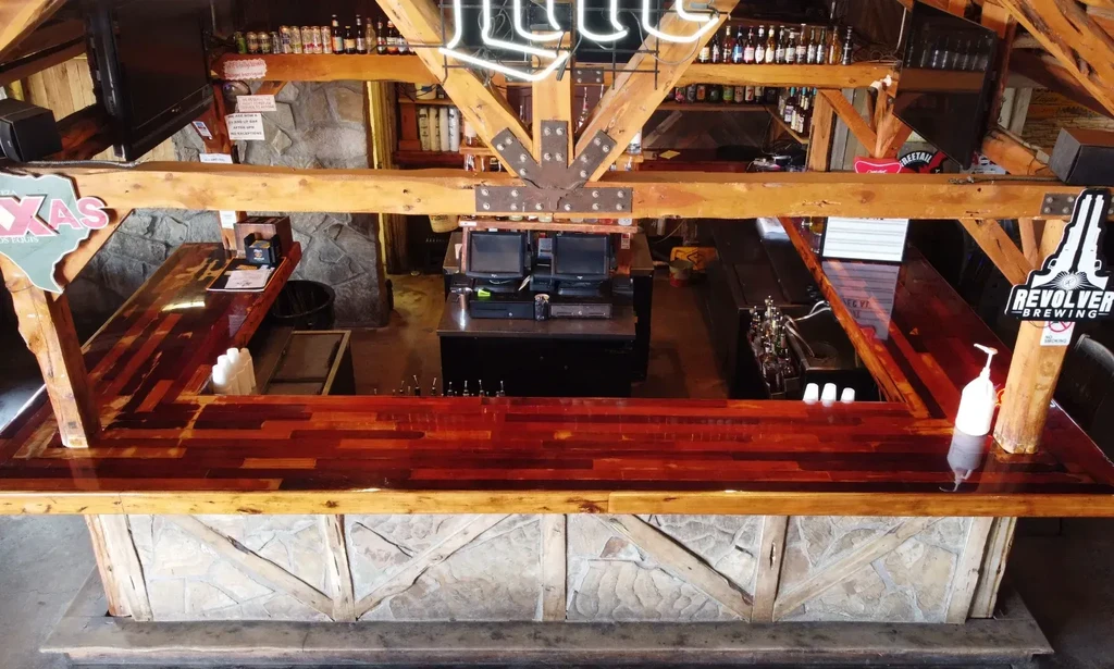 U-shaped wooden bar in a rustic lodge-style interior with signs.
