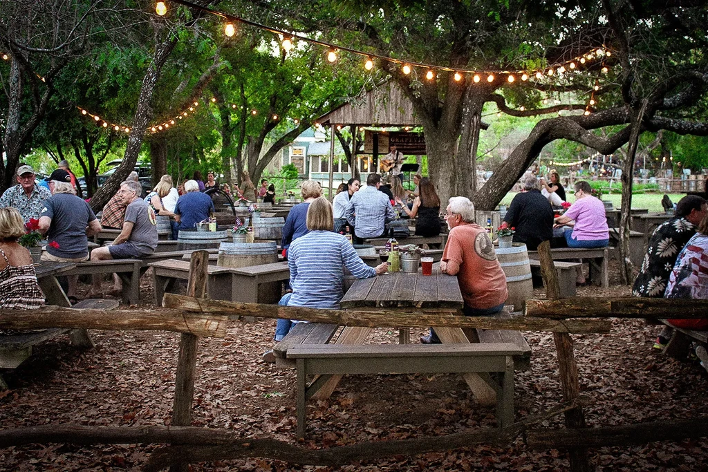 People enjoy an outdoor beer garden with string lights and live music.