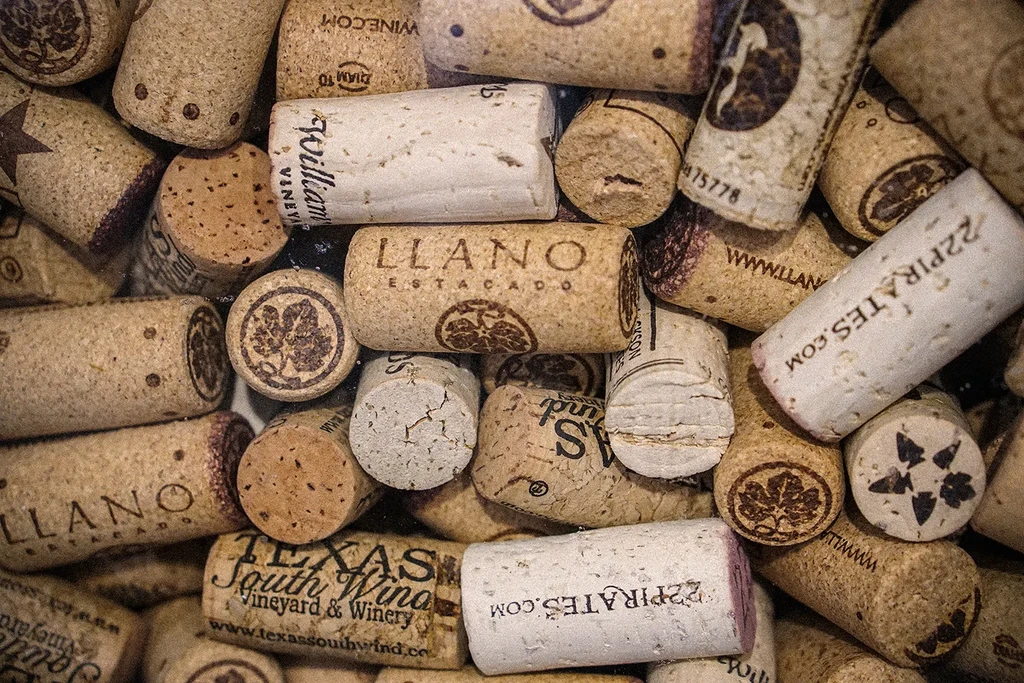Numerous used wine corks, tightly packed, with visible winery names and stains.