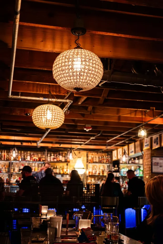 Ornate spherical chandeliers illuminate a sophisticated bar with patrons.