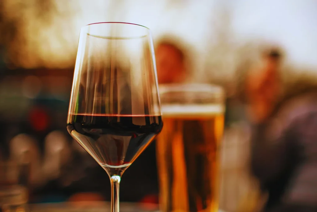 Elegant red wine glass in focus, blurry bar scene behind.
