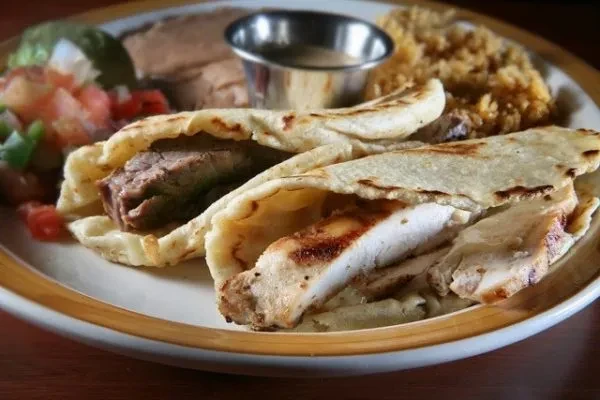 Plate with steak and chicken tortillas, Spanish rice, refried beans, salsa.