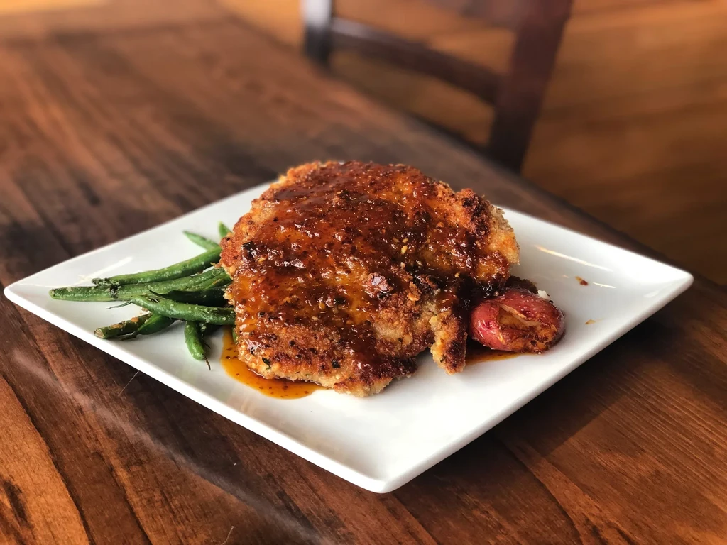 Plated breaded cutlet, glossy sauce, green beans, and roasted potato.