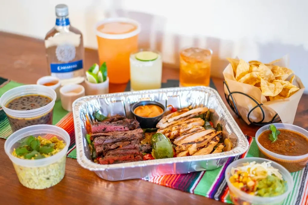 Mexican chicken and steak fajitas with sides, chips, and tequila.