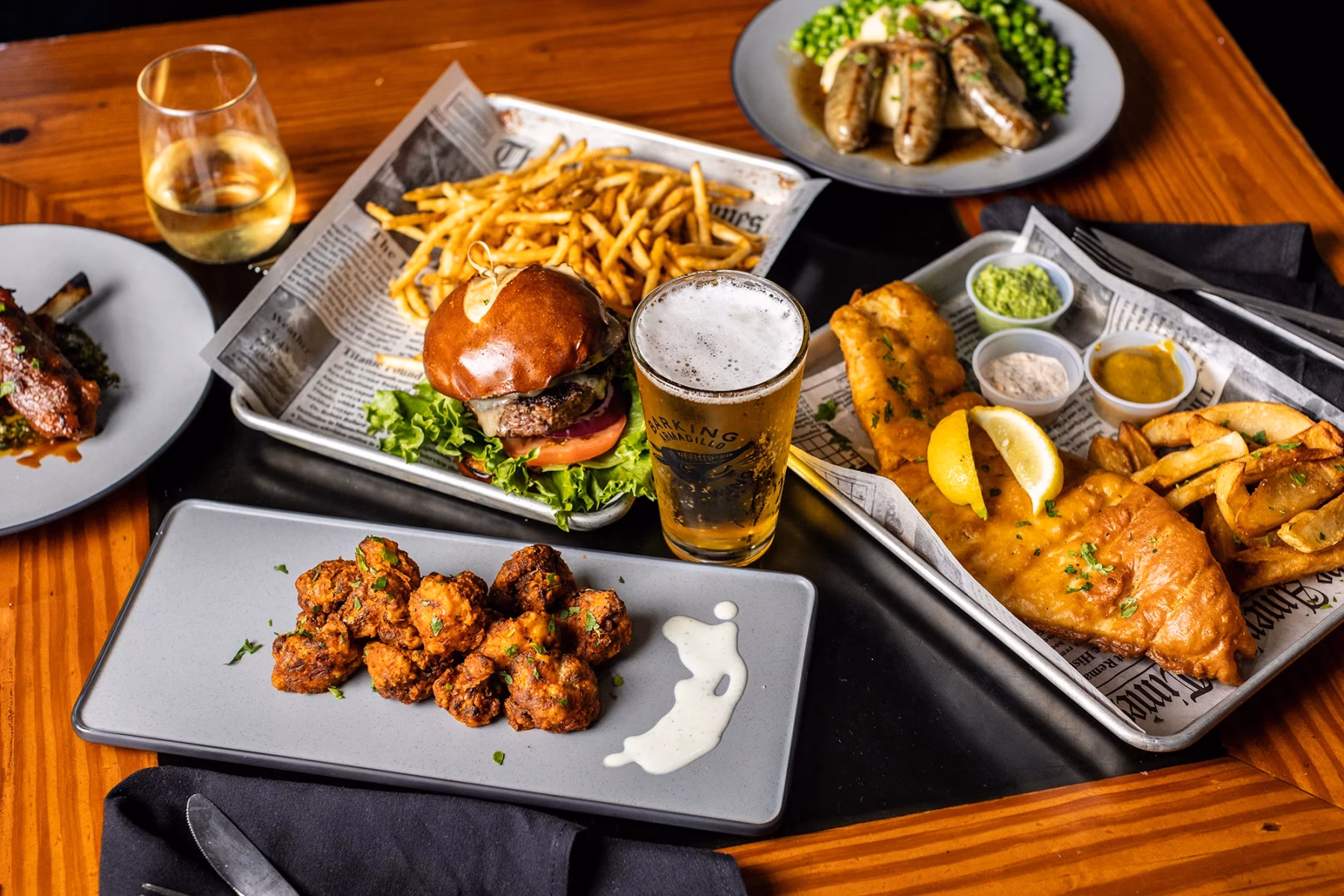 A variety of pub food and drinks displayed on a dark table.
