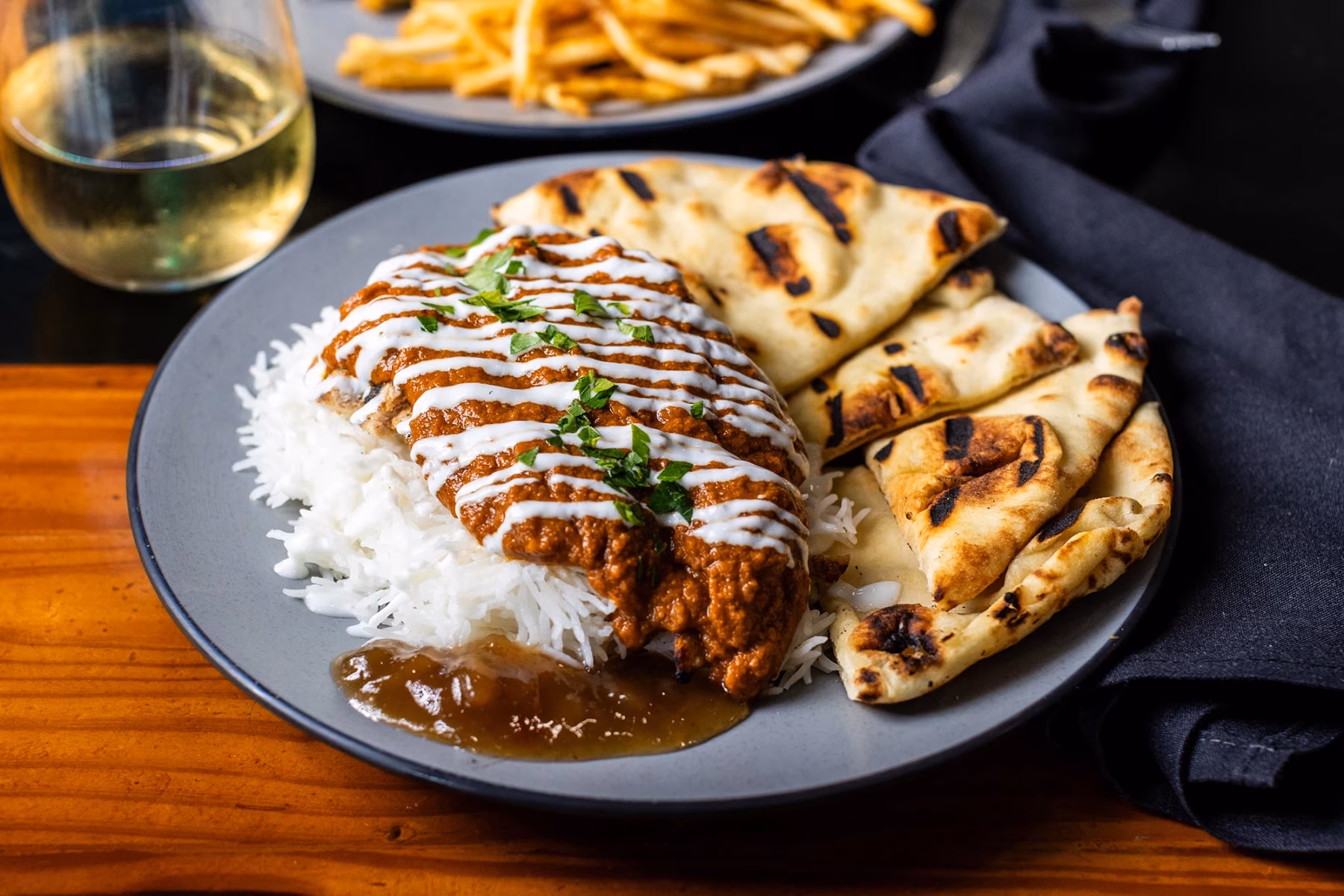 Plate with orange-red sauced dish, white rice, naan, and chutney.