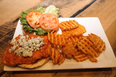 Buffalo chicken sandwich with blue cheese, lettuce, tomato, and waffle fries.