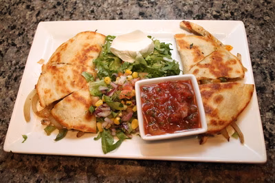 Quesadilla with salsa, sour cream, shredded lettuce, and corn salsa.