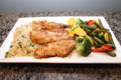Seasoned fish fillets, rice with peas, and steamed mixed vegetables.