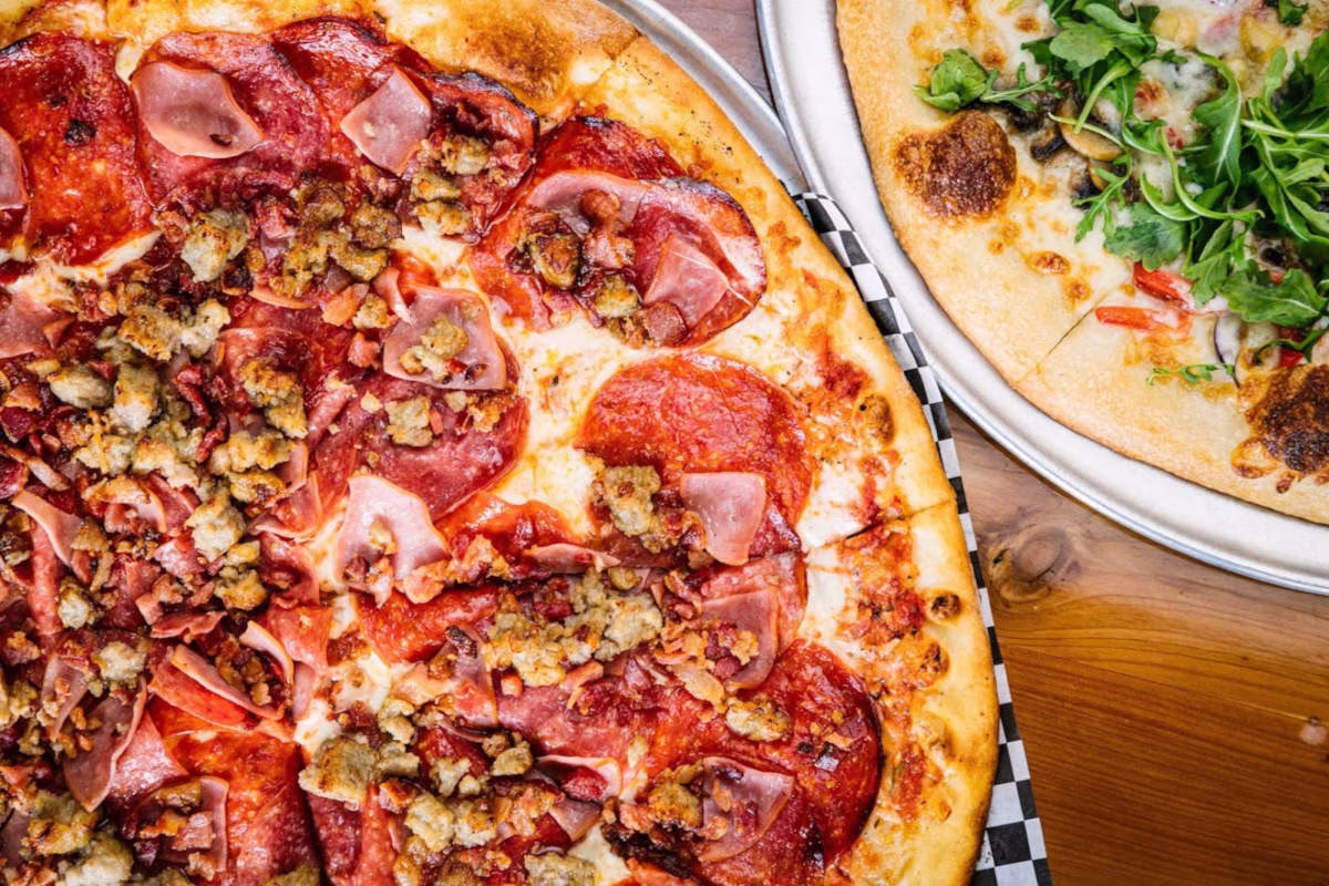 Two pizzas: one with meat, the other with vegetables and arugula.