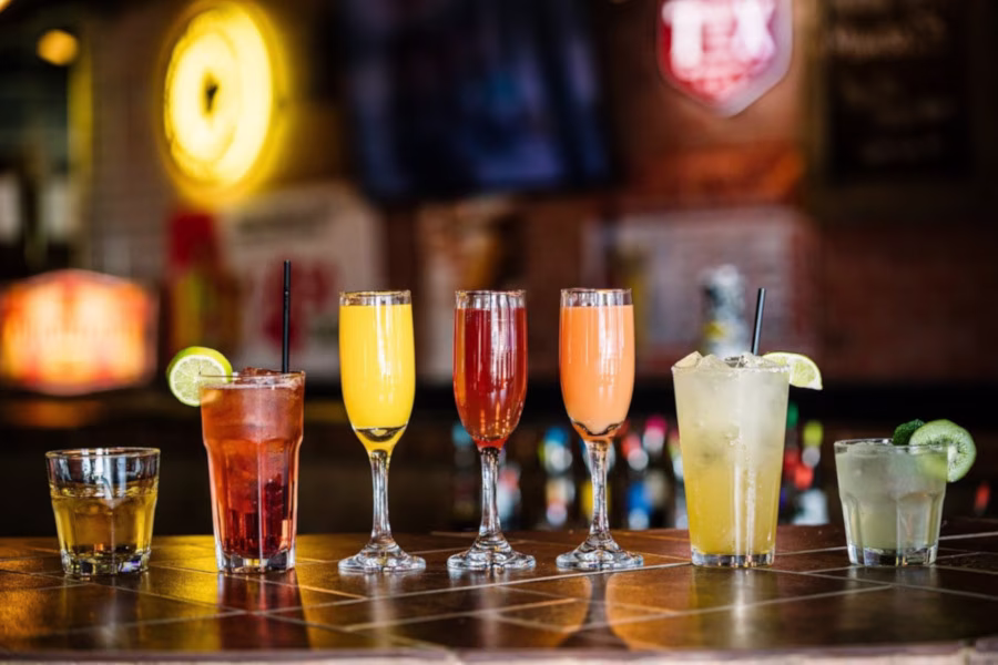 Assorted colorful drinks in various glasses on a bar counter.