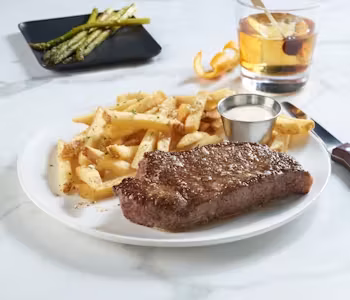 Plate of steak and fries, with asparagus and an Old Fashioned.