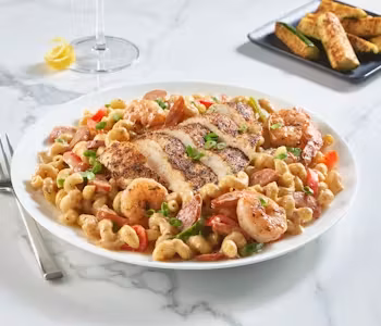 Macaroni pasta with sliced chicken, shrimp, and sausage.
