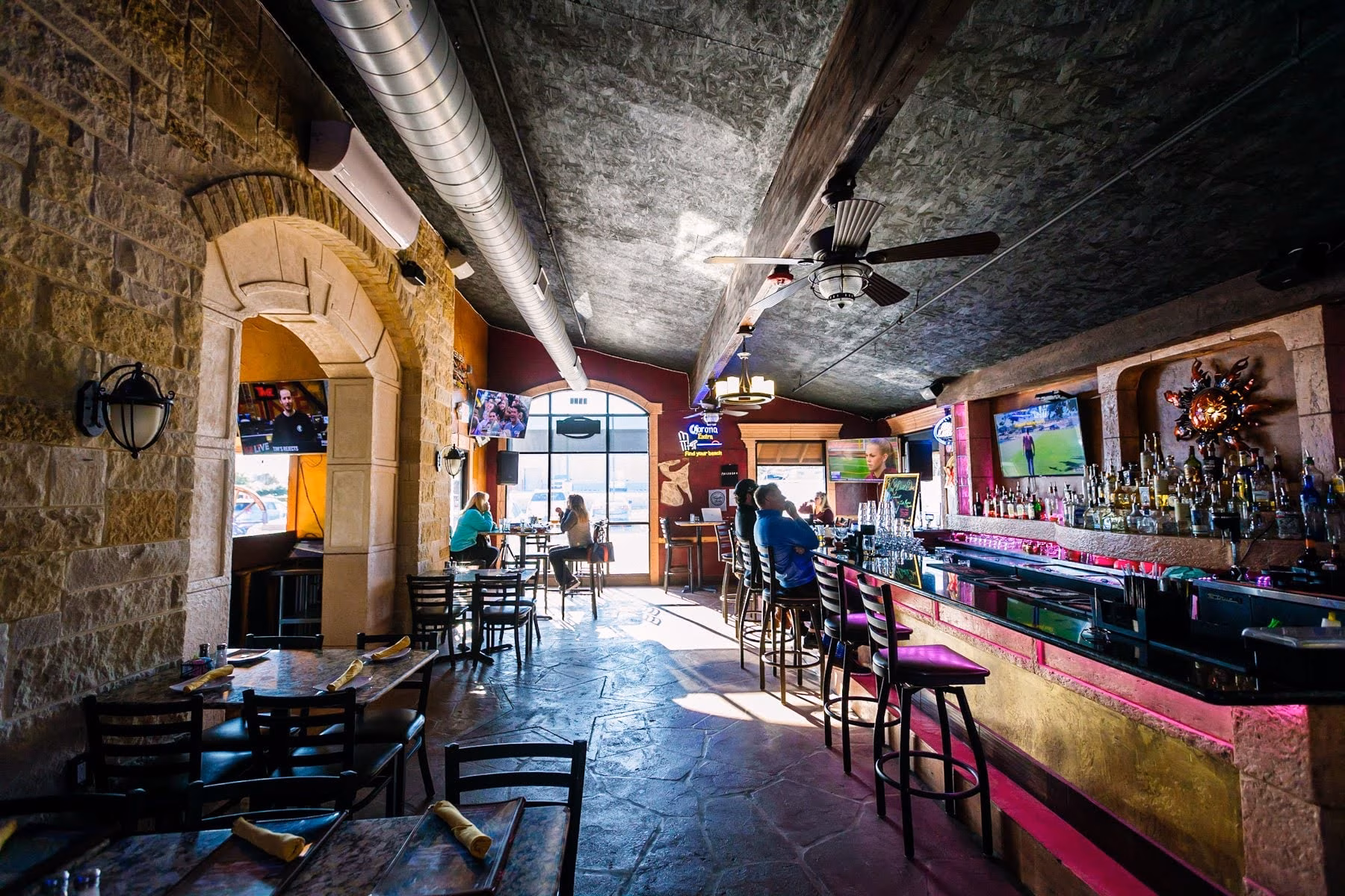 Restaurant and bar interior with stone walls, tables, and seated patrons.