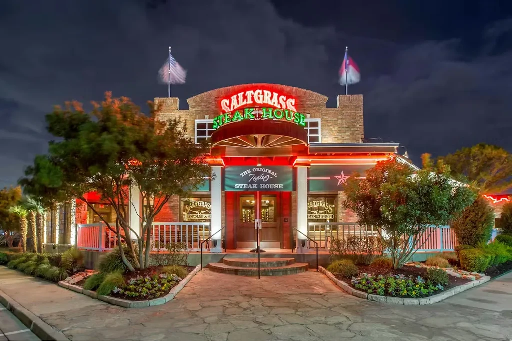 Saltgrass Steak House exterior at night, glowing red and green neon signs.